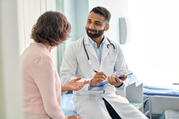 Indian,male,doctor,consulting,senior,old,patient,filling,form,at
